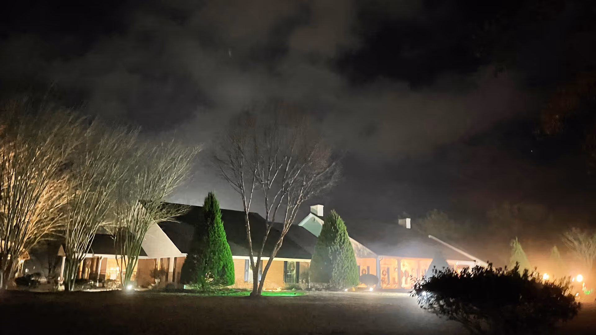 Night exterior of Southern Living Assisted Living building with trees and dim lights.