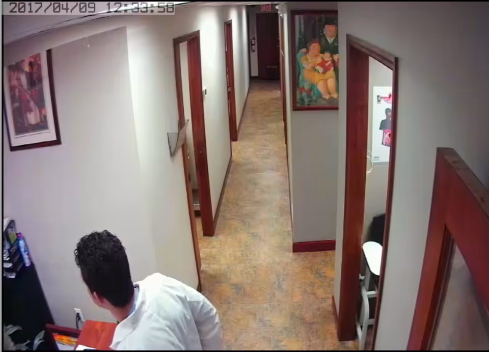 A hallway in a senior living facility with doors along both walls and a staff member.
