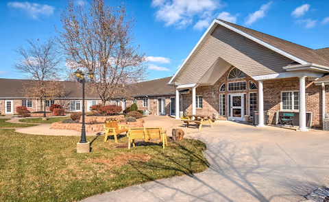 Exterior view of Elderberry Health Care facility with a courtyard and wooden benches.