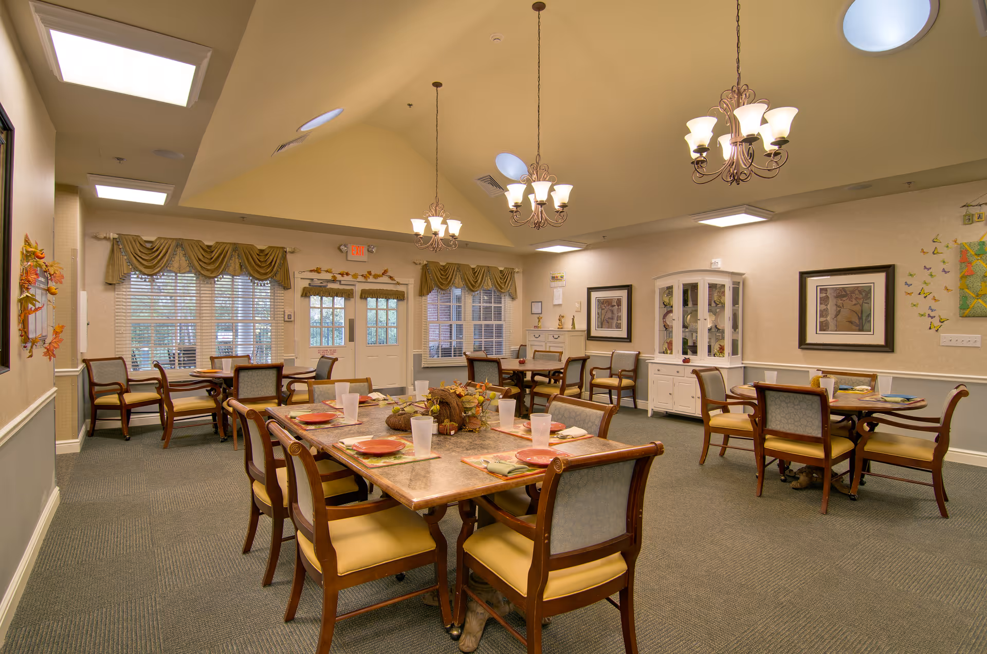 Bright dining room with tables set for meals and decorative chandeliers.