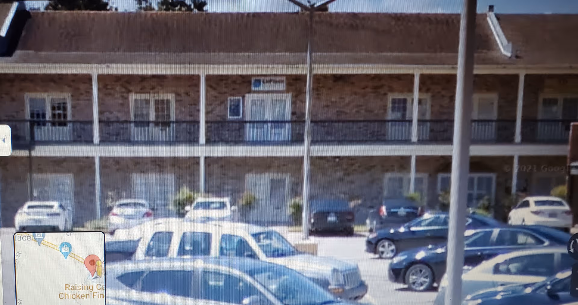 Exterior view of Kacen's Kare senior living facility with a brick building, balcony, and parked cars.