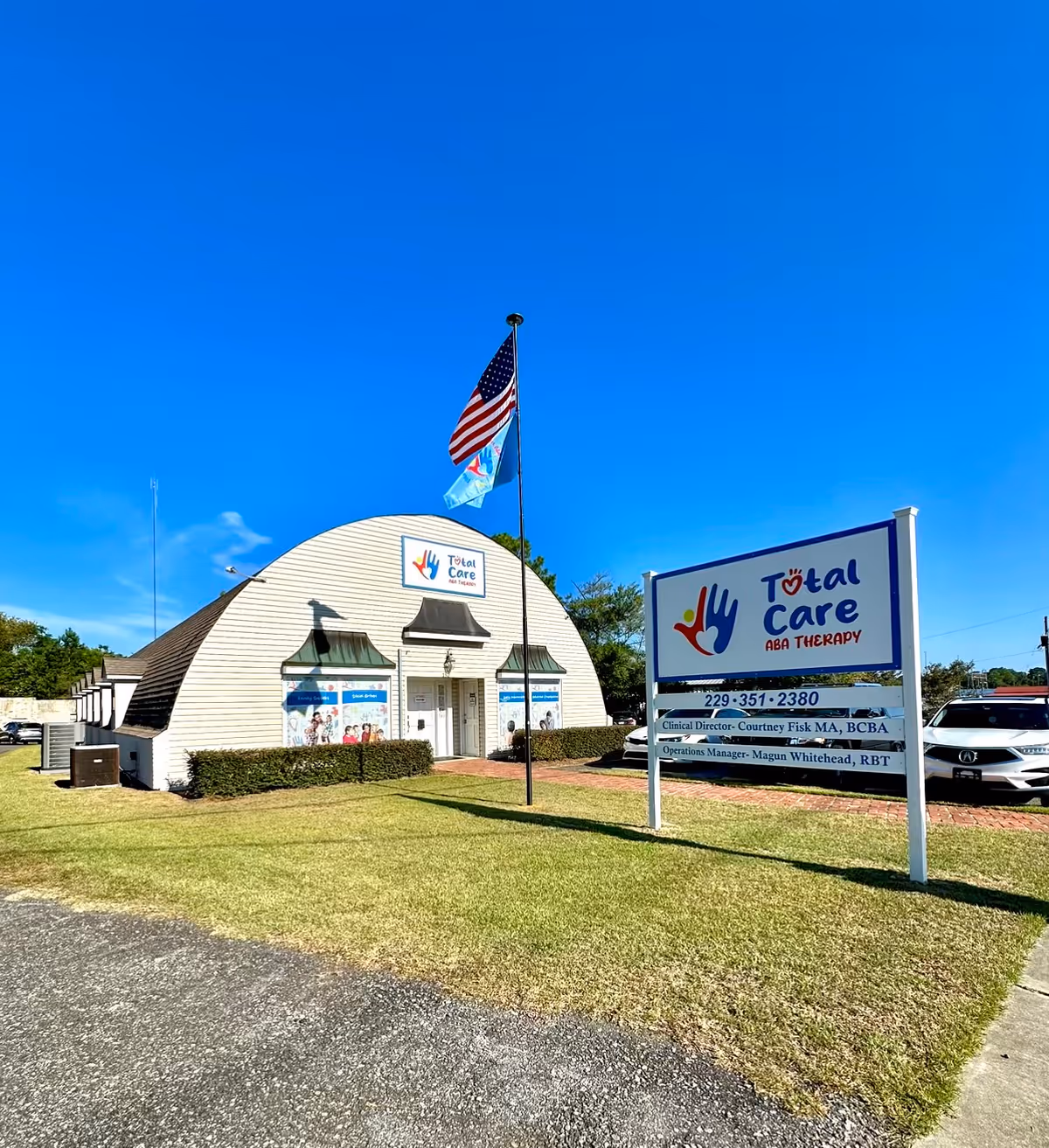 A Total Care ABA Therapy building with a curved roof and sign under clear blue sky.