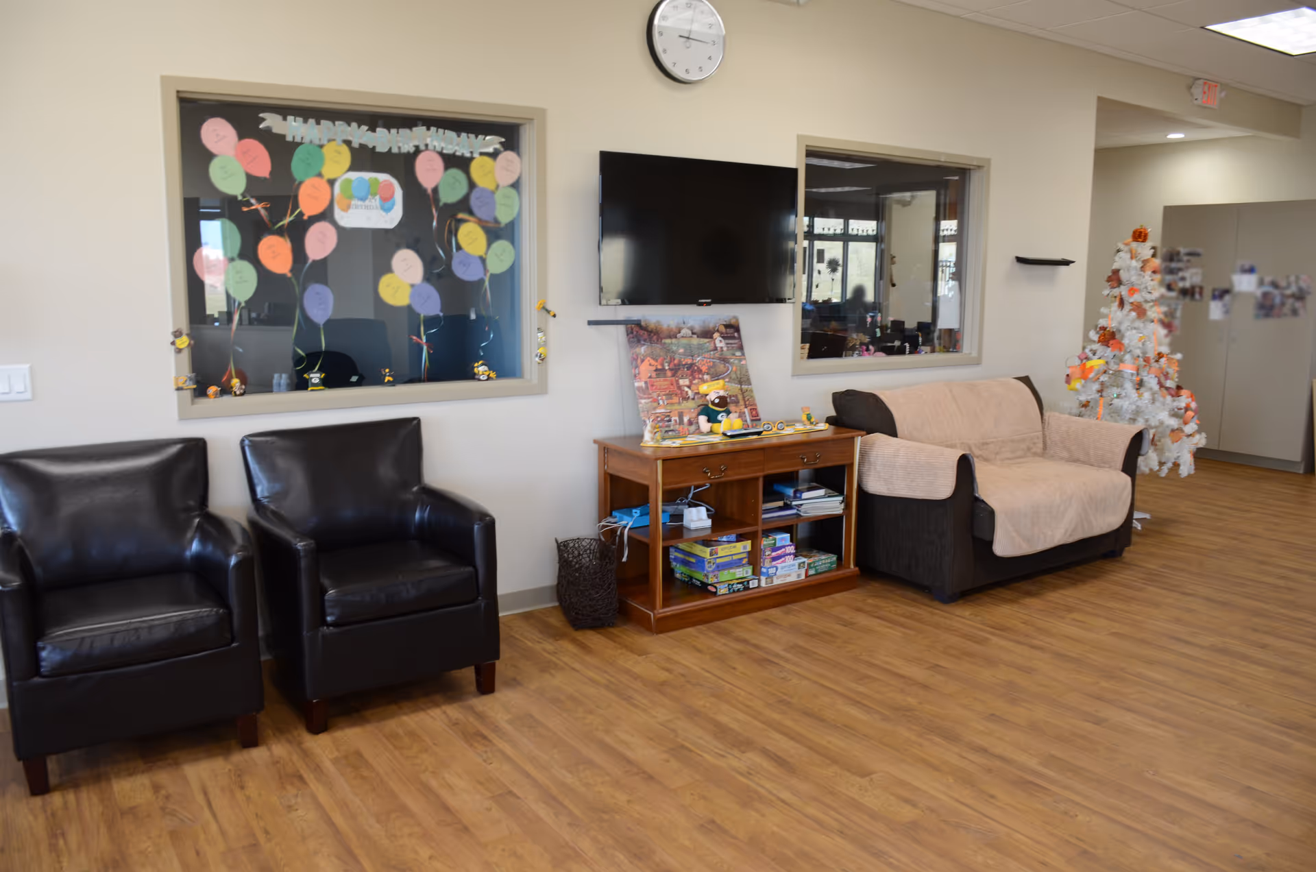 Cozy facility lobby with black armchairs, a sofa, a shelf, TV, and a Christmas tree