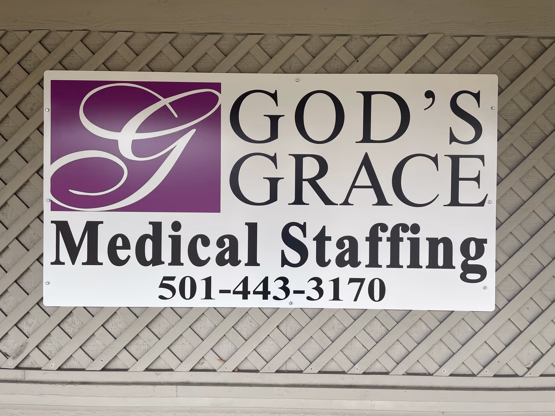 A large sign on a lattice wall advertising God's Grace Medical Staffing.