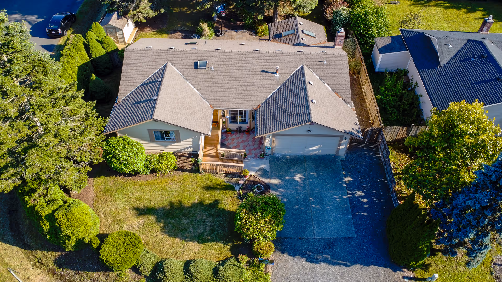 Aerial view of a single-story home with a large driveway and manicured front yard.