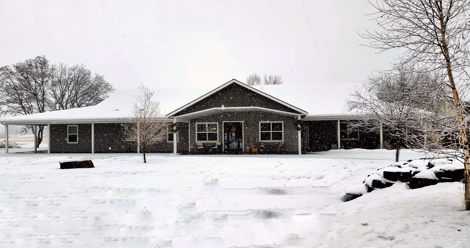 A snow-covered, single-story facility with a central entrance and a covered front porch.