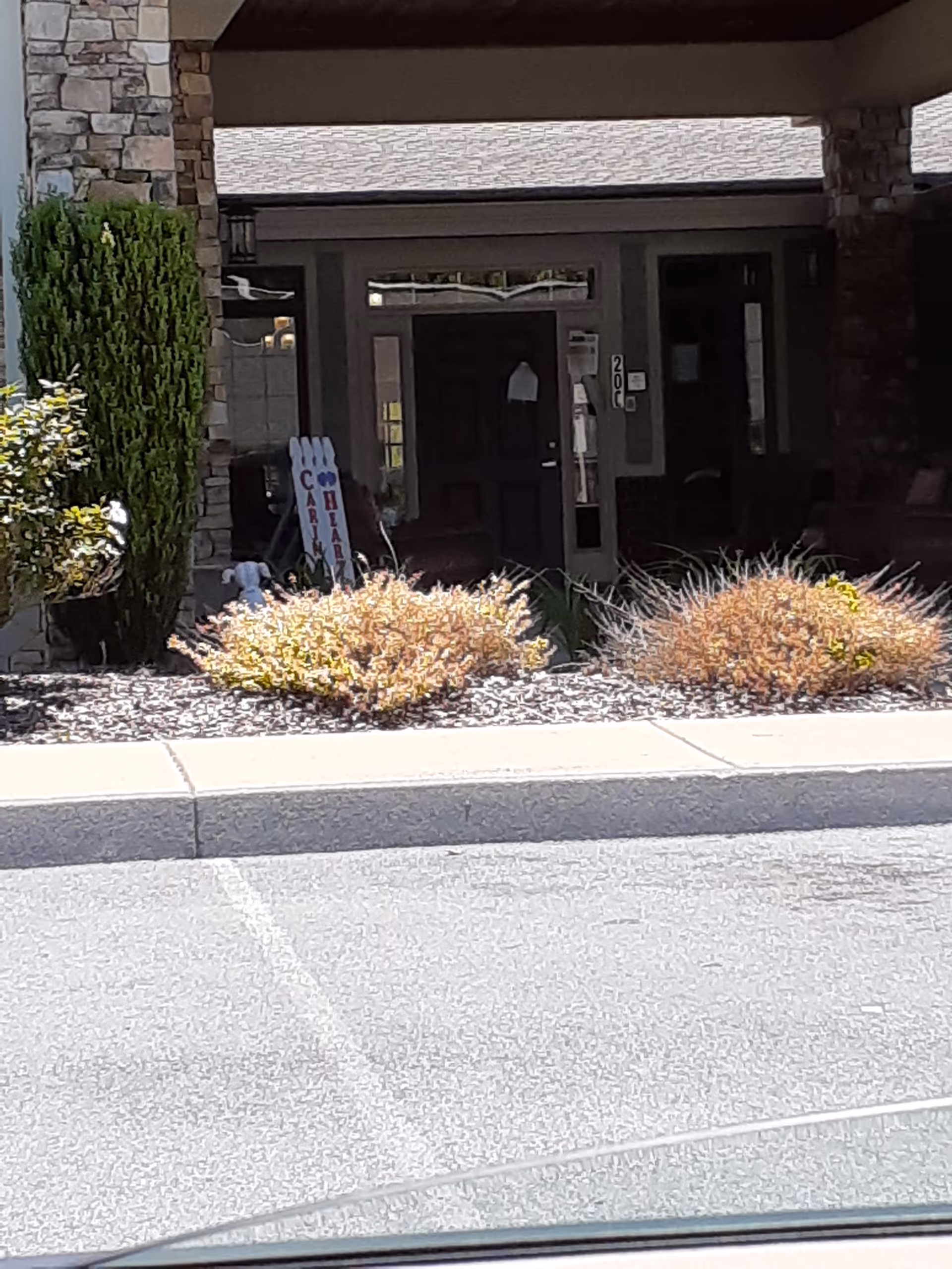 Entrance to The Village at Allandale senior living, featuring stone columns and glass doors.