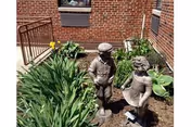 Brick facility exterior with garden plants and two child statues in a courtyard.
