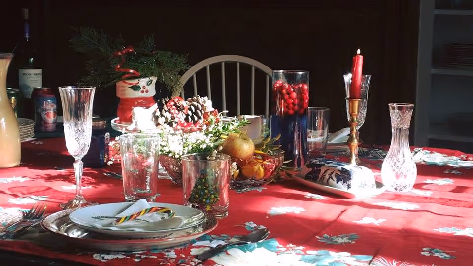 Festive holiday dinner table in a dining room with glassware, plates, and centerpiece.