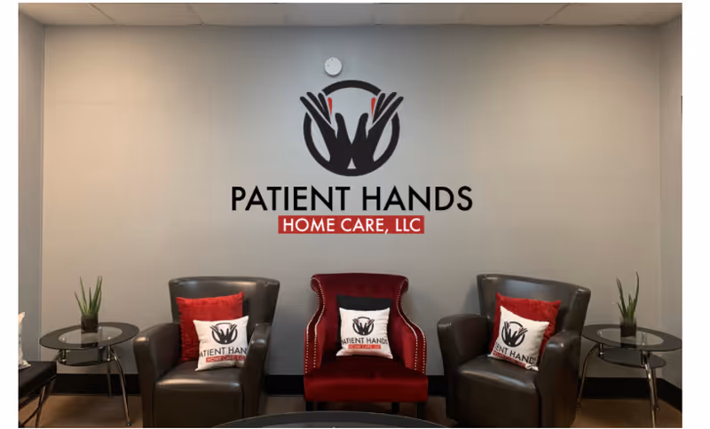 Indoor lobby with three chairs, side tables, plants, and a Patient Hands Home Care LLC logo.