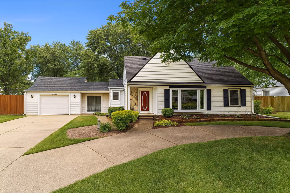 Front view of a suburban house with a curved driveway and manicured lawn.