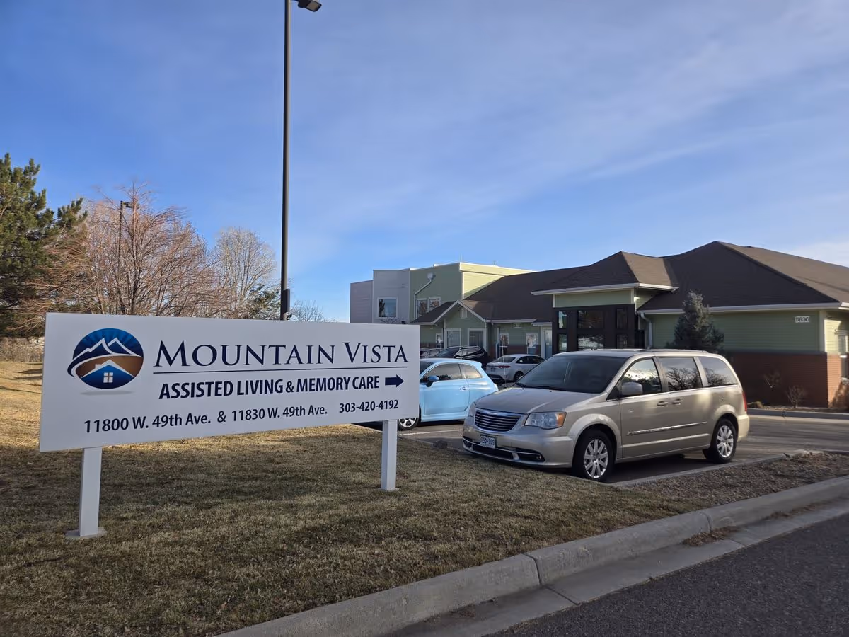 Sign for Mountain Vista Assisted Living & Memory Care in front of the facility building with parked cars.