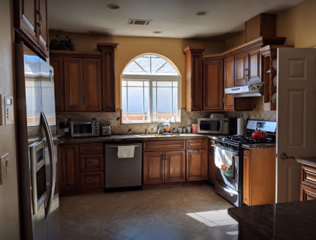 Traditional wooden kitchen with stainless appliances and an arched window.