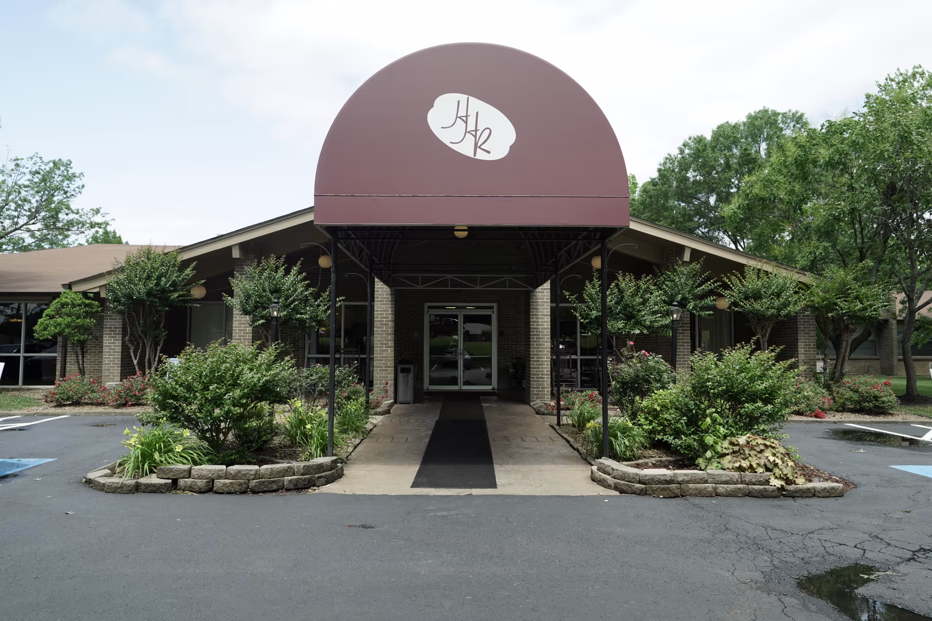 Entrance to Huntingdon Health and Rehabilitation Center with a curved maroon canopy and landscaped walkway.