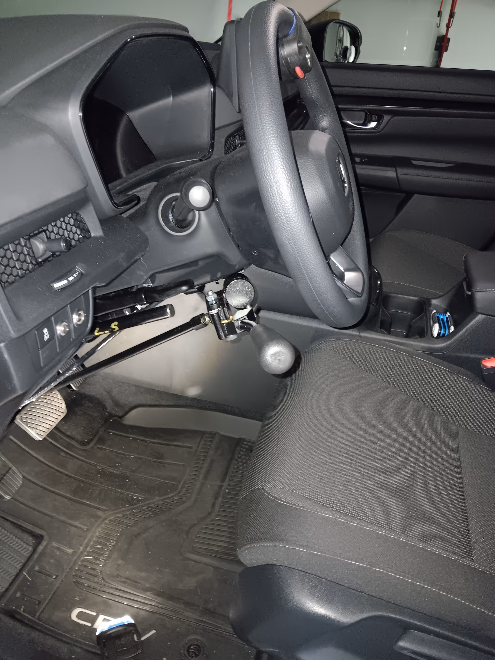 Close-up view of a car's driver's seat, steering wheel, pedals, and dashboard.
