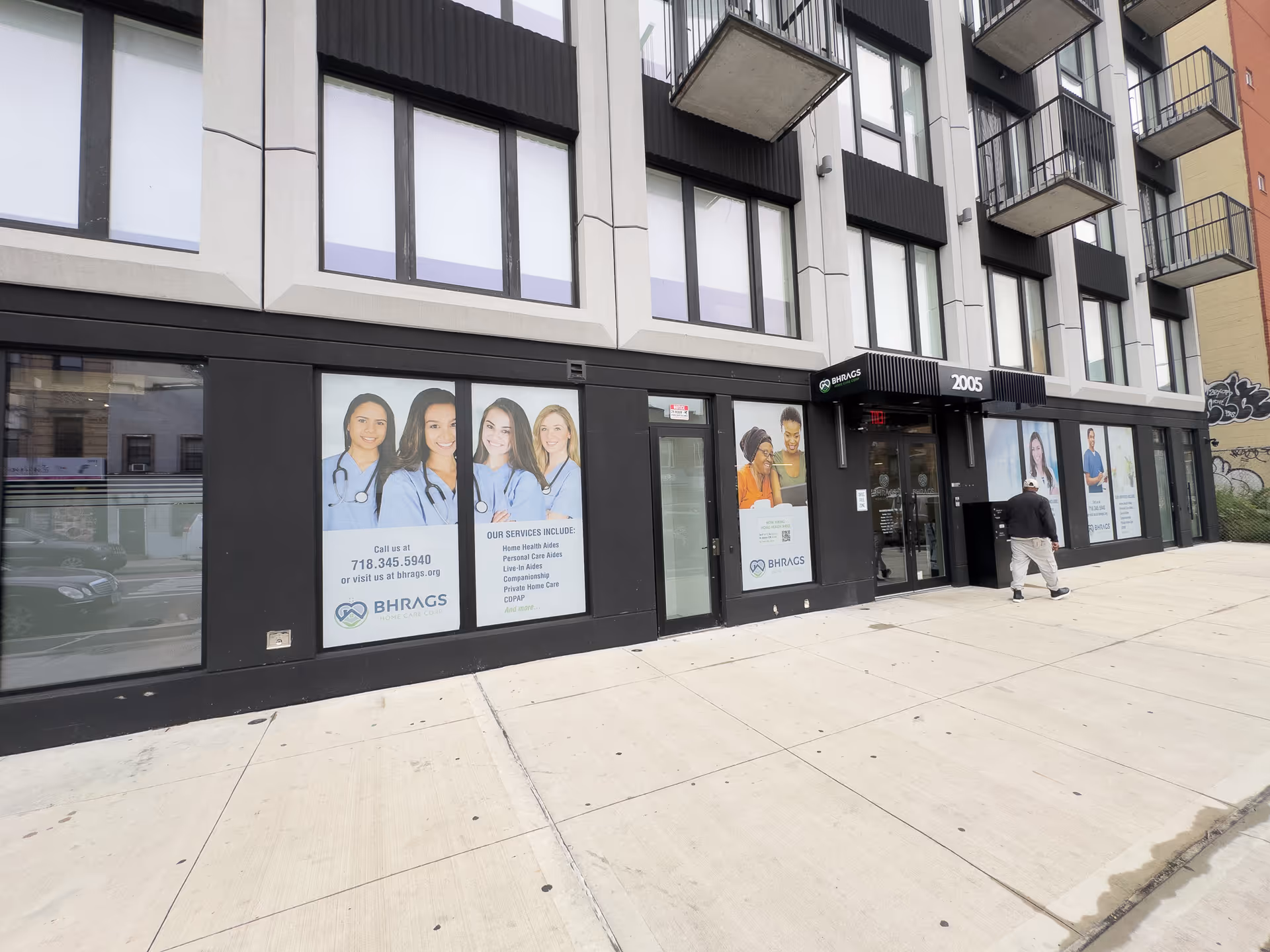 Modern building storefront with BHRAGS Home Care signage and a person walking outside.