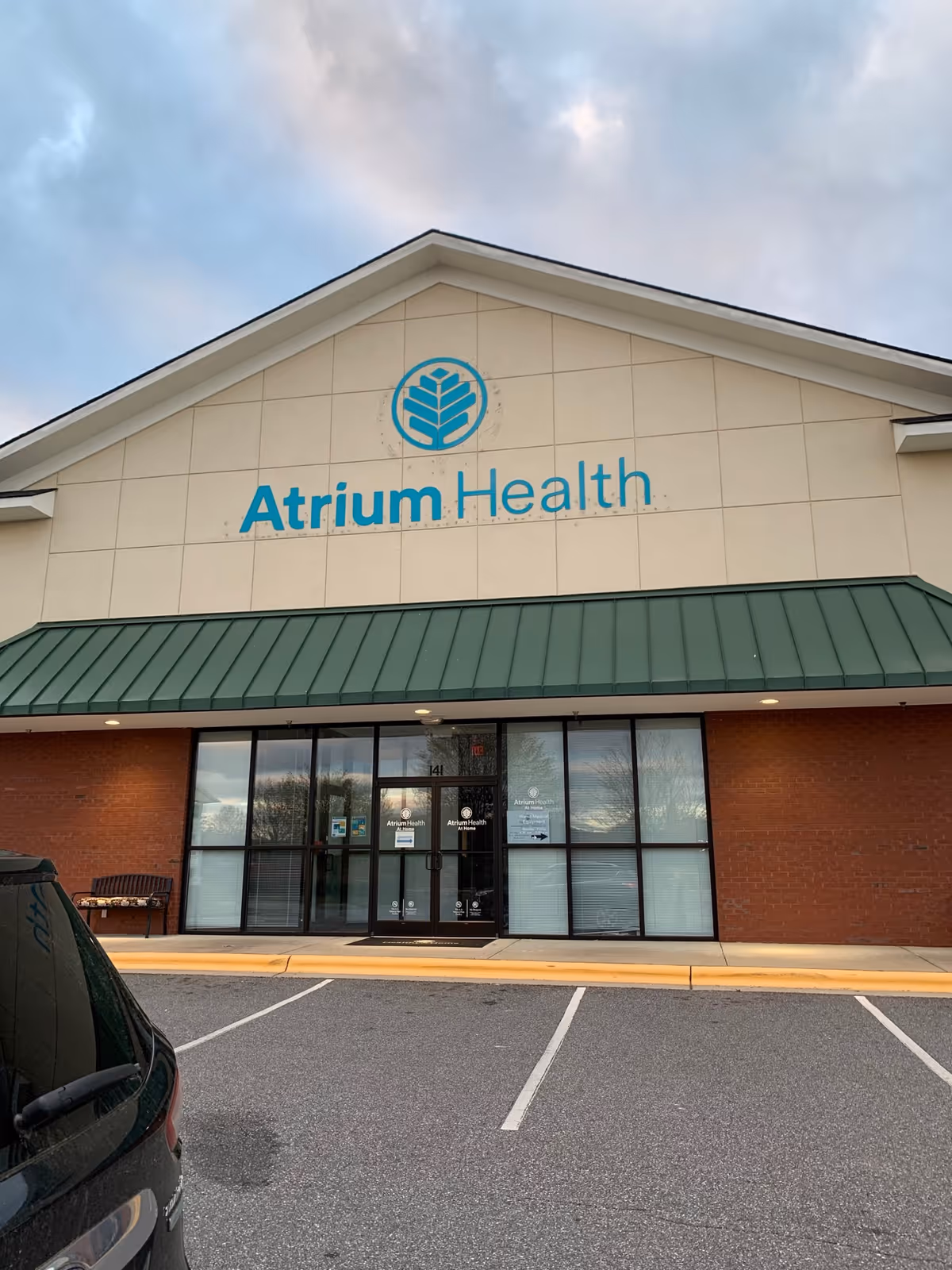 Exterior storefront of Atrium Health At Home with glass entrance and parking.