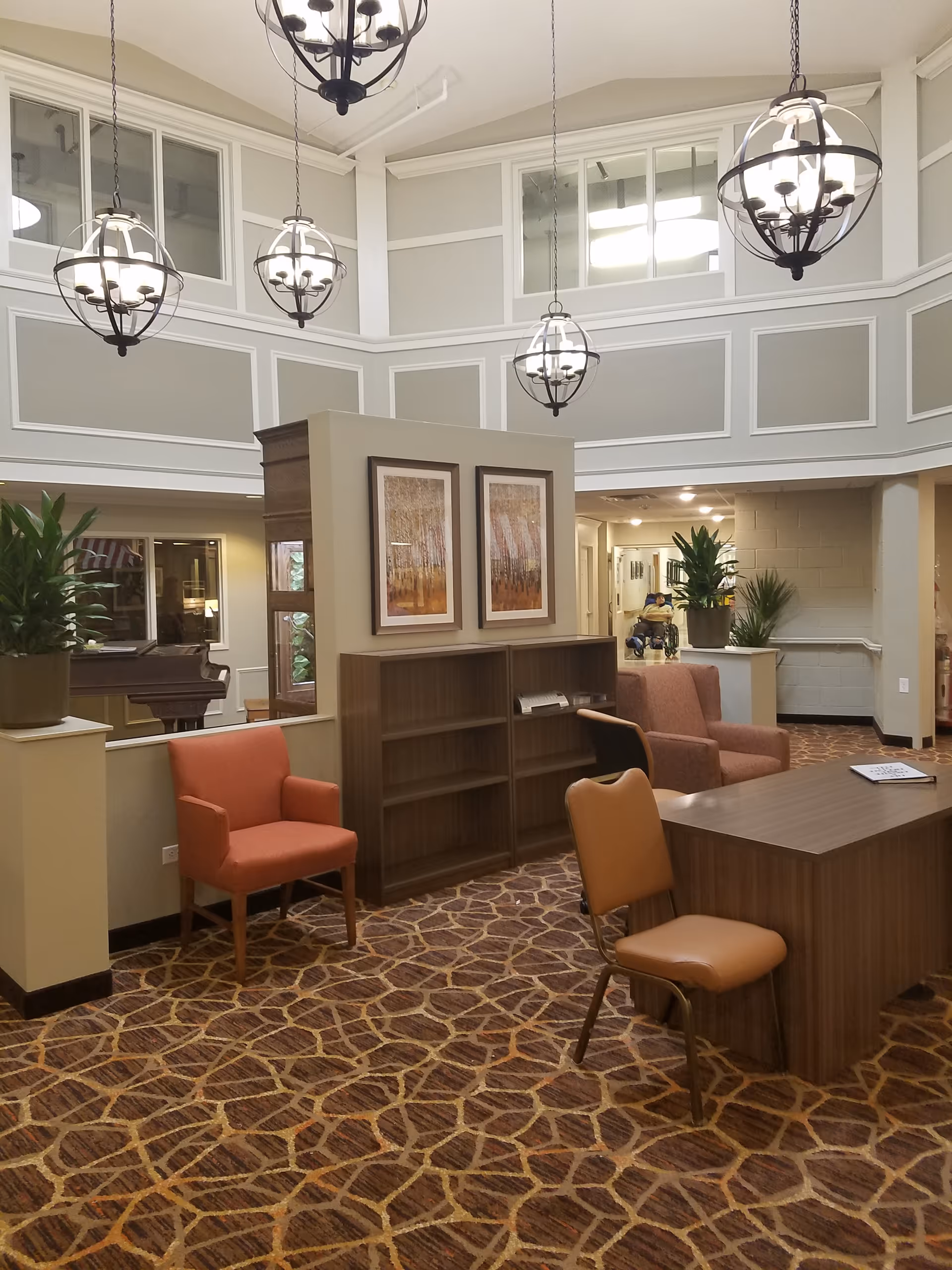 Lobby/common area featuring seating, bookshelves, plants, and spherical chandeliers at Alden Park Strathmoor.