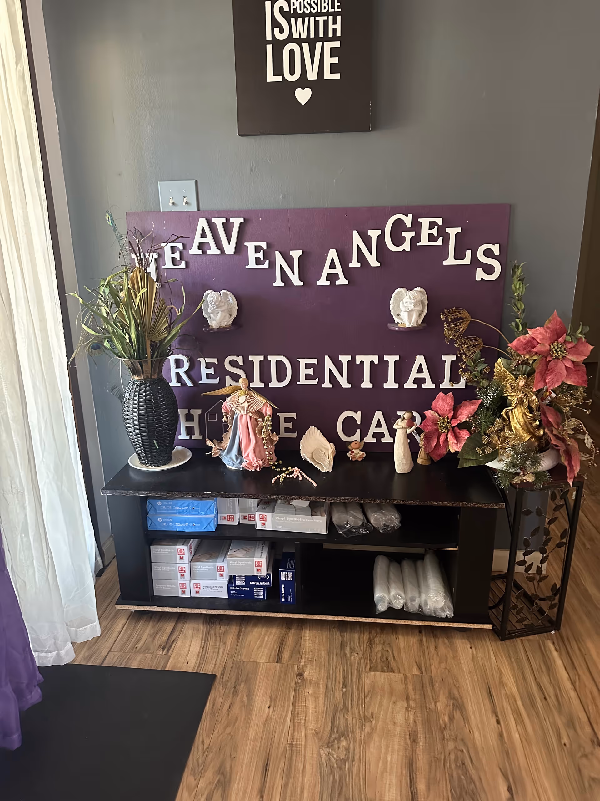 Interior hallway with purple Heaven Angels Residential Care sign, angels, and decorative plants.