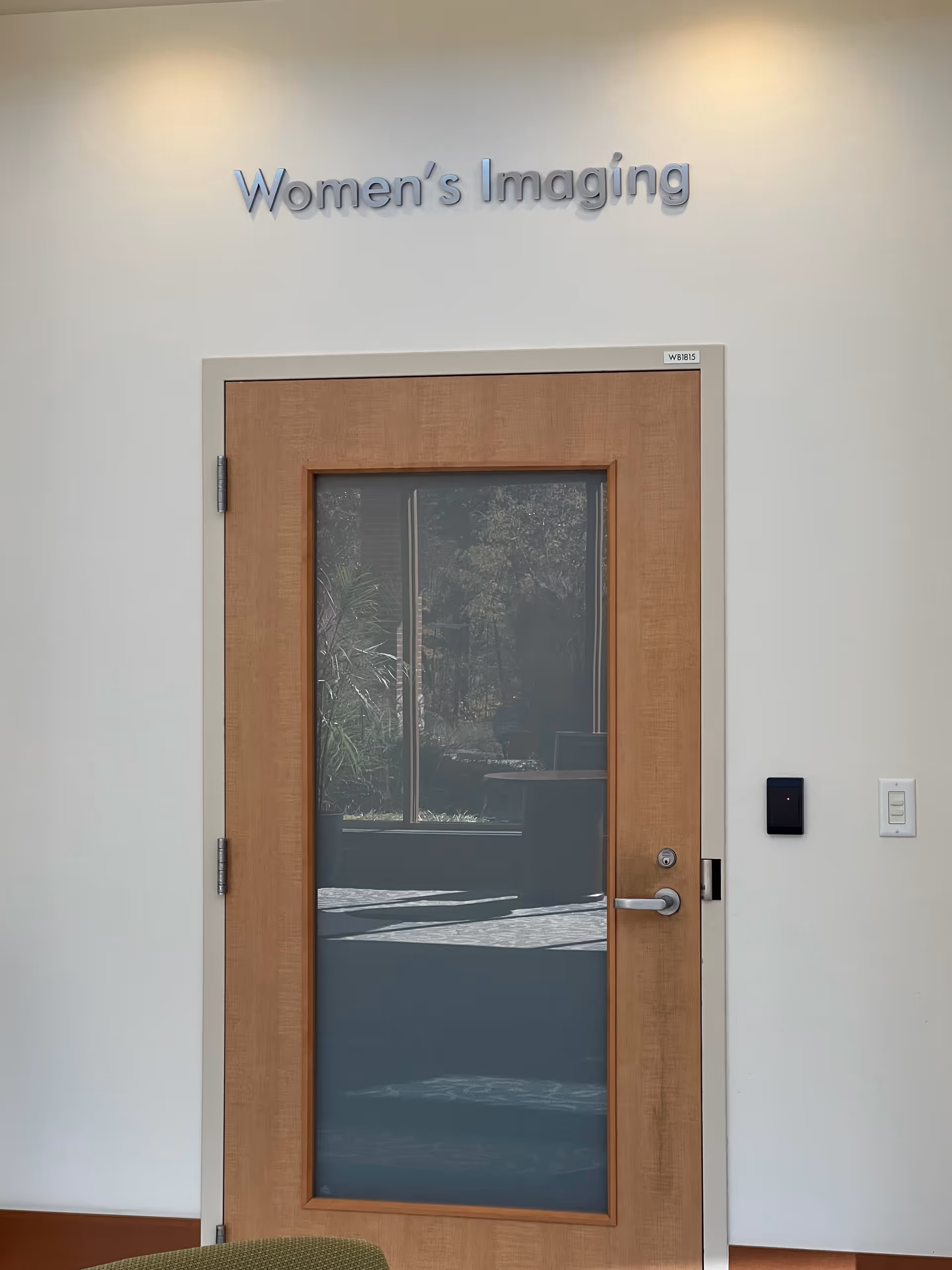 Wooden-framed glass door with 'Women's Imaging' sign in an interior hallway.