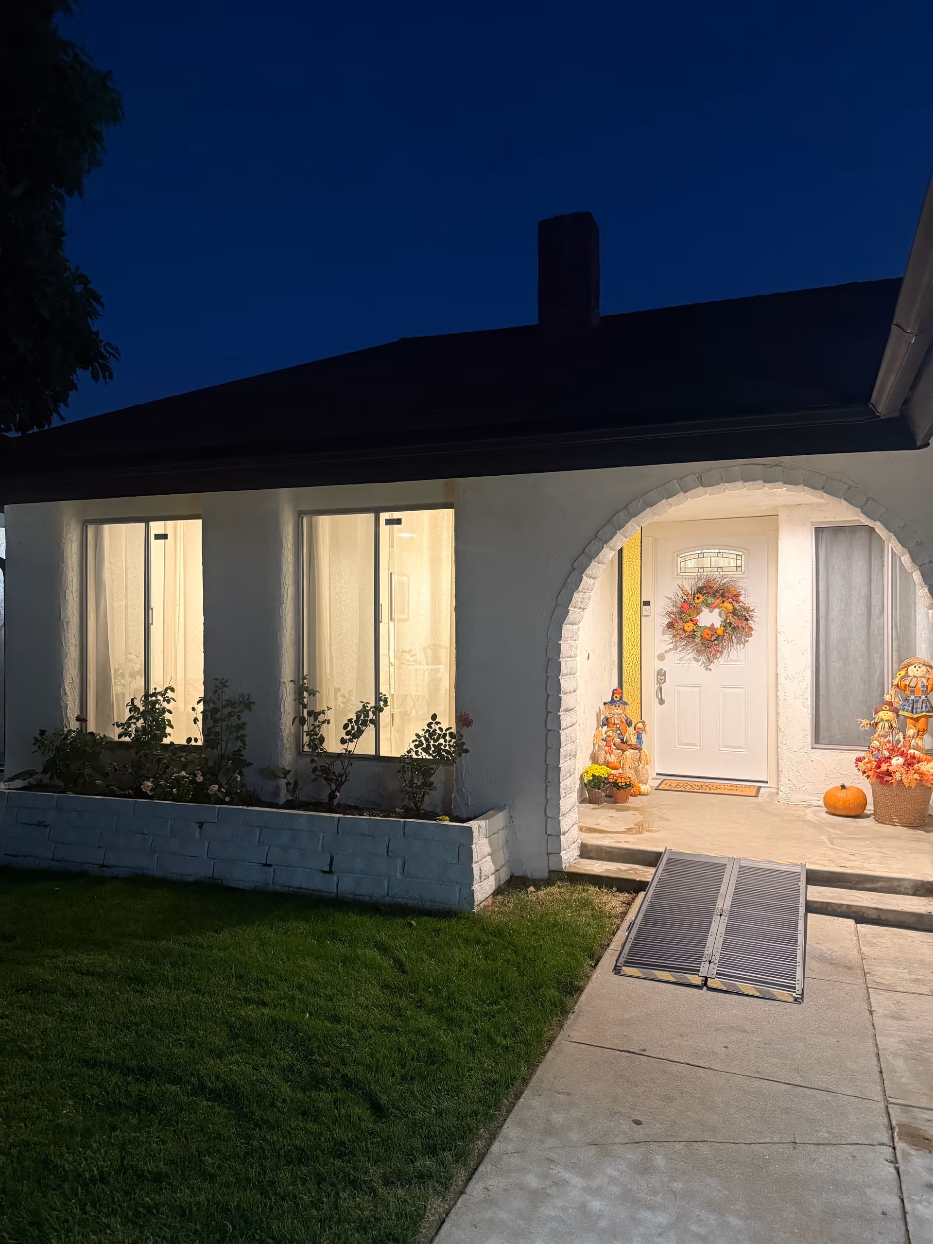 Front entrance of a single-story senior living home with autumn decorations.