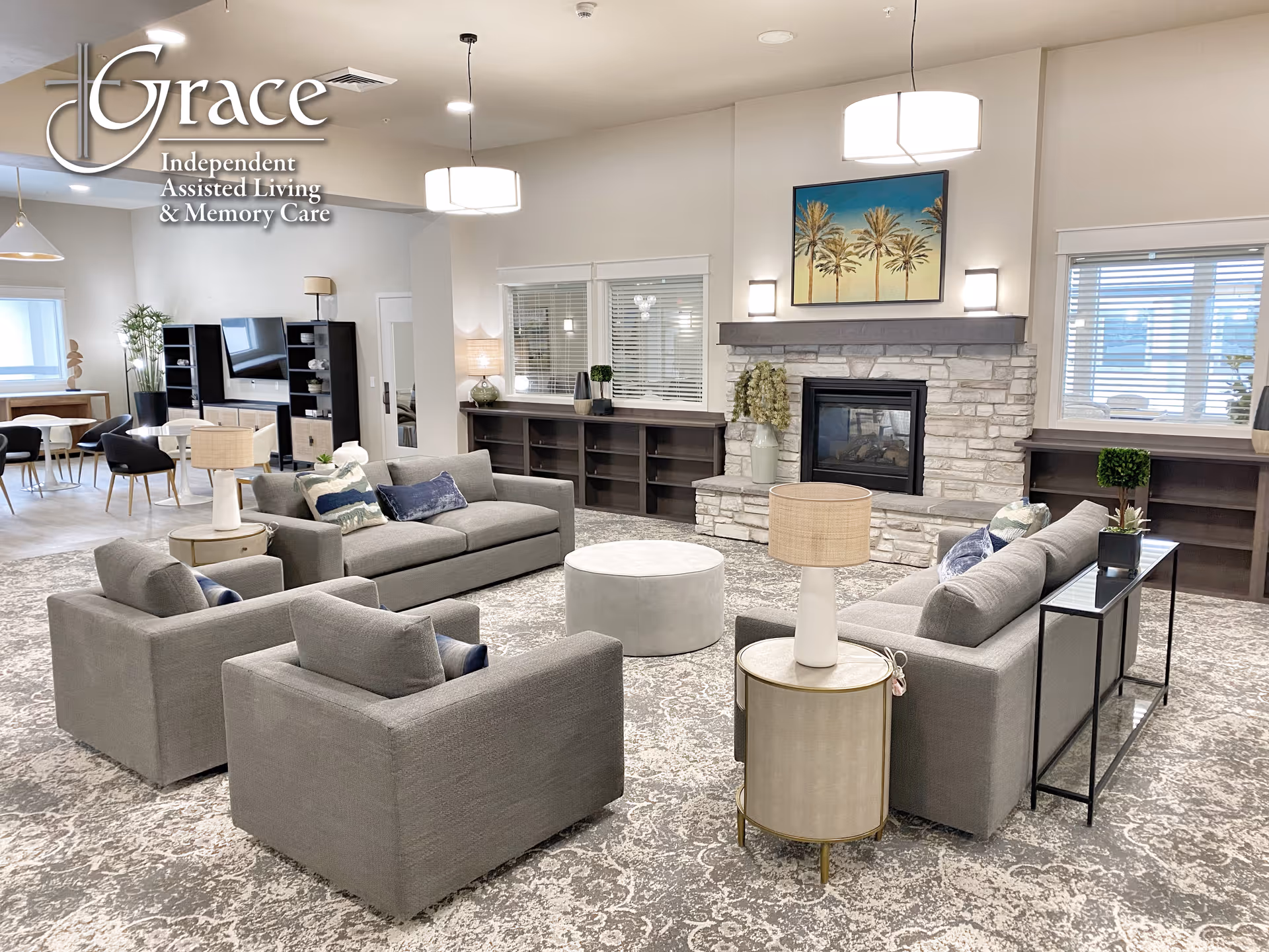 Spacious assisted living lounge with gray sofas, fireplace, and modern decor.