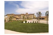 Exterior view of Evergreen at Plano with landscaped lawn and beige multi-story building.