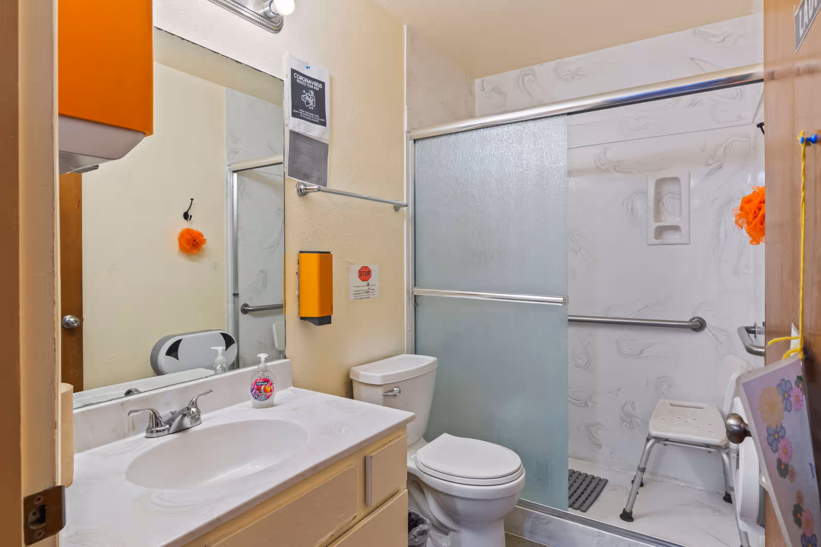 Accessible bathroom in a senior facility with sink, toilet, and enclosed shower.
