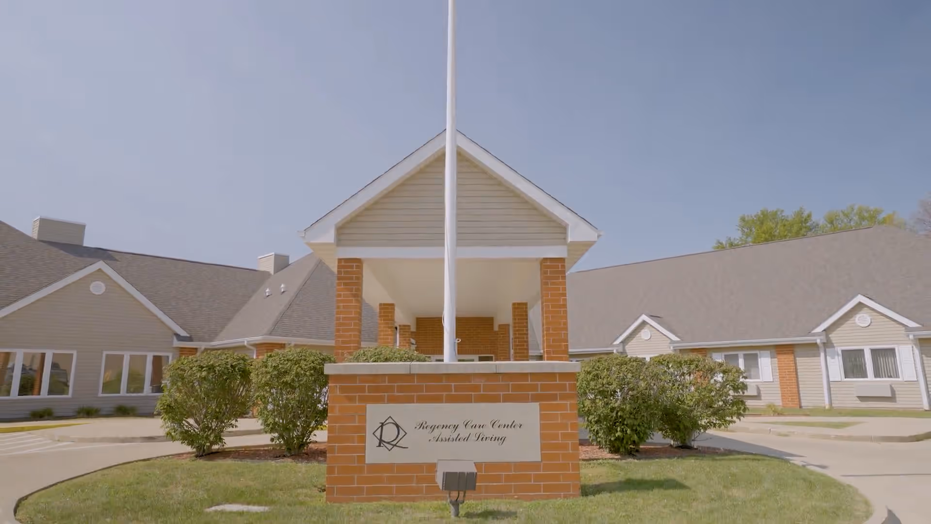 Front exterior of Regency Care Center with brick sign and flagpole.