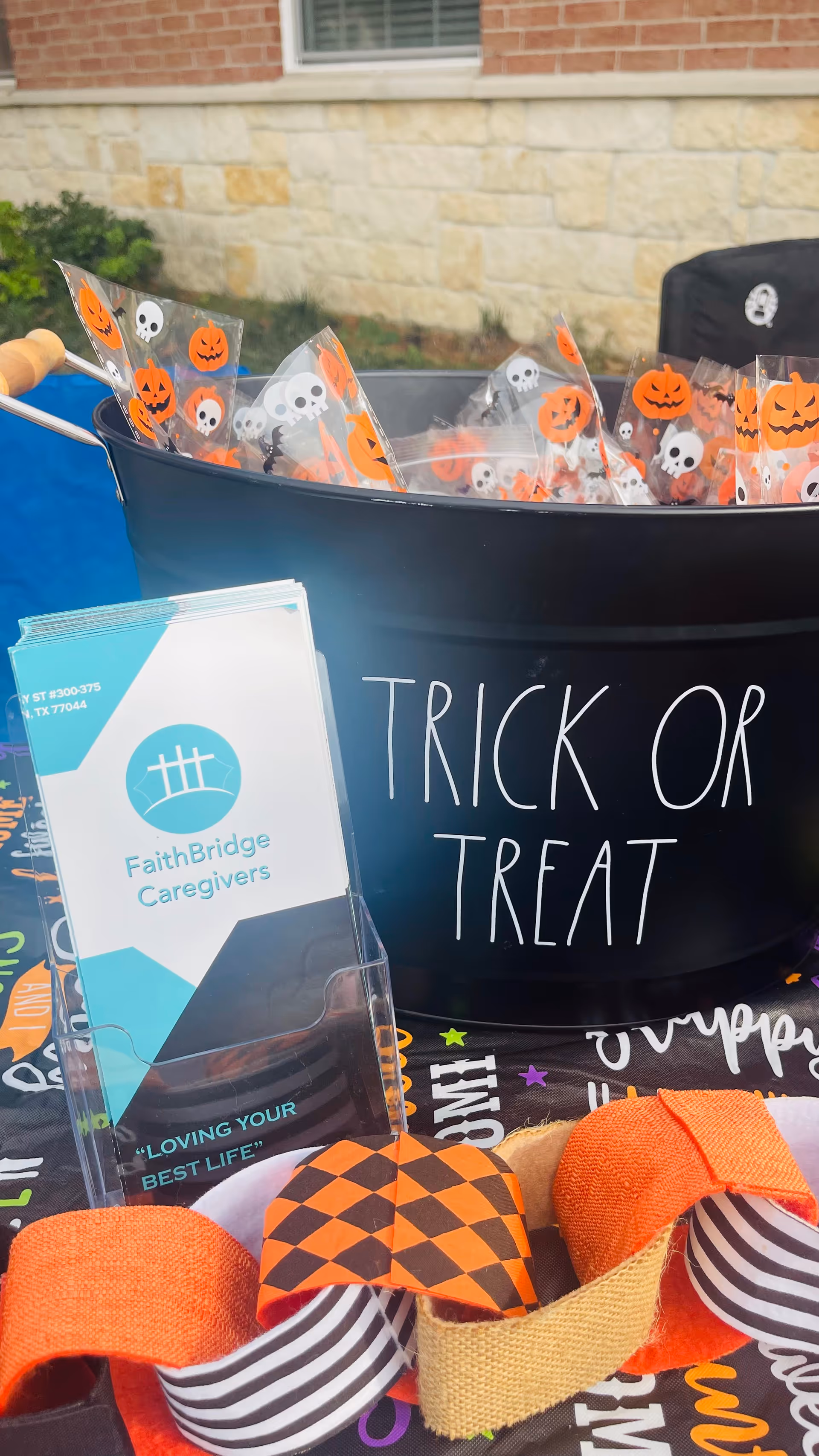 Outdoor display featuring a Trick or Treat bucket and FaithBridge Caregivers pamphlets.