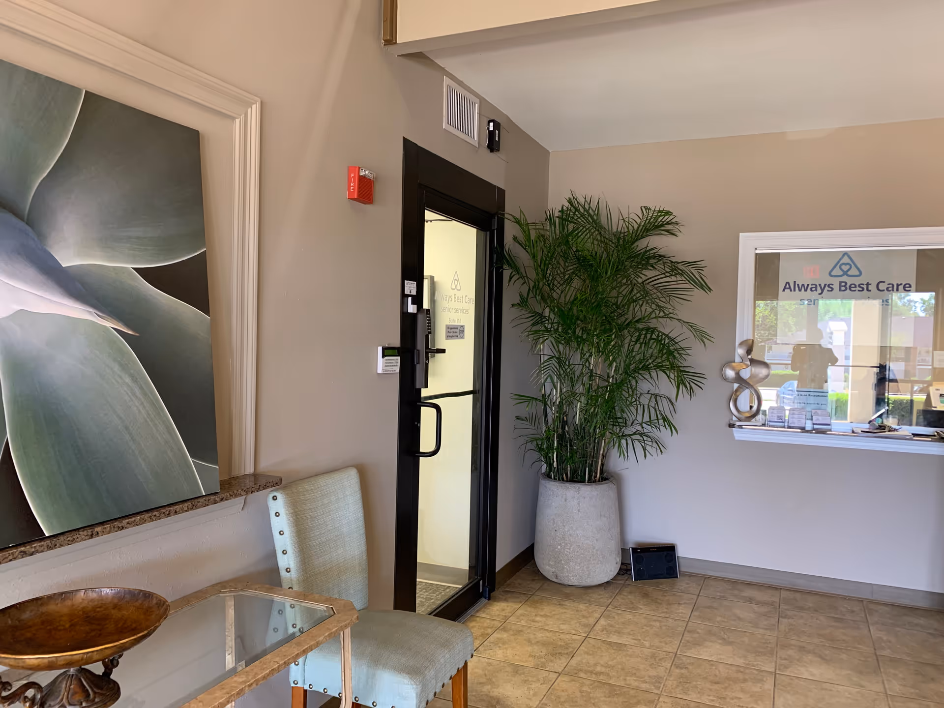 Lobby area with seating, a large plant, and a reception window.