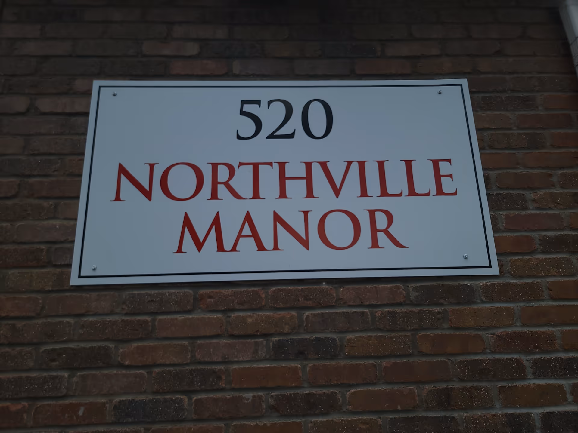 White sign reading 520 Northville Manor mounted on brick exterior wall.