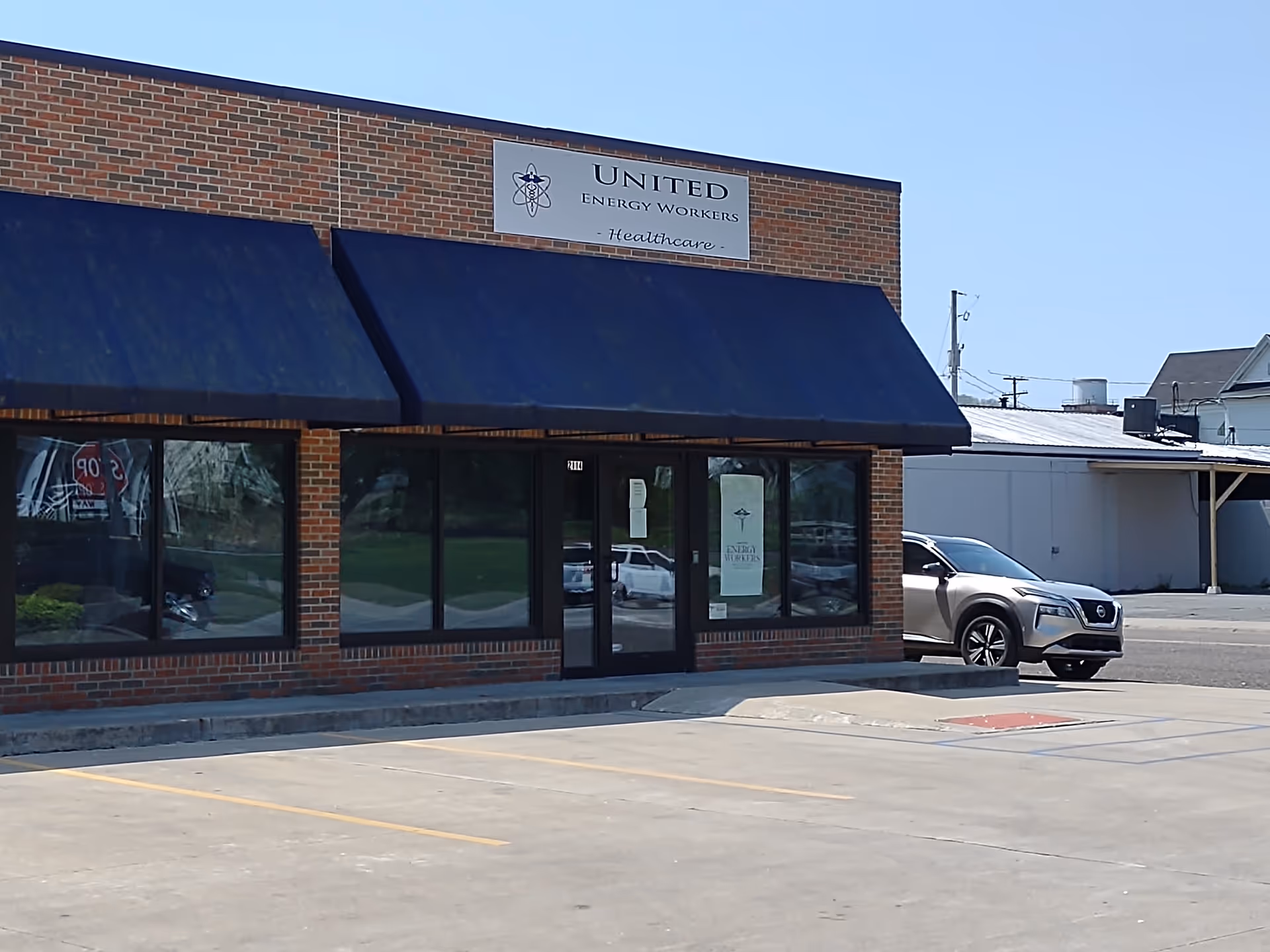 Front of a brick building with blue awnings and United Energy Workers Healthcare sign.