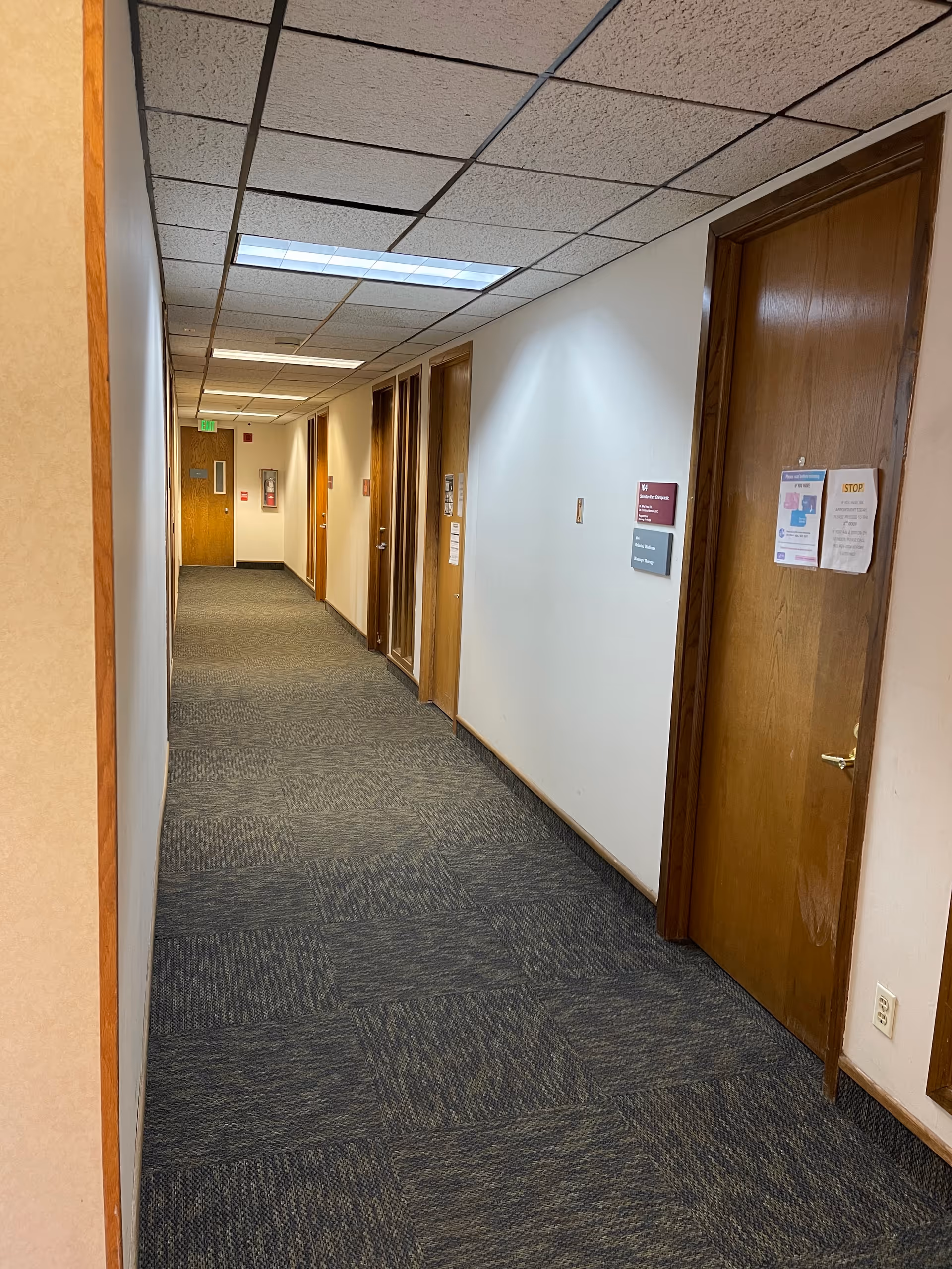 Interior hallway of a senior facility with doors, carpet, and overhead lighting.