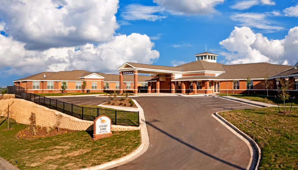 Exterior view of a brick senior living facility with driveway and entrance.