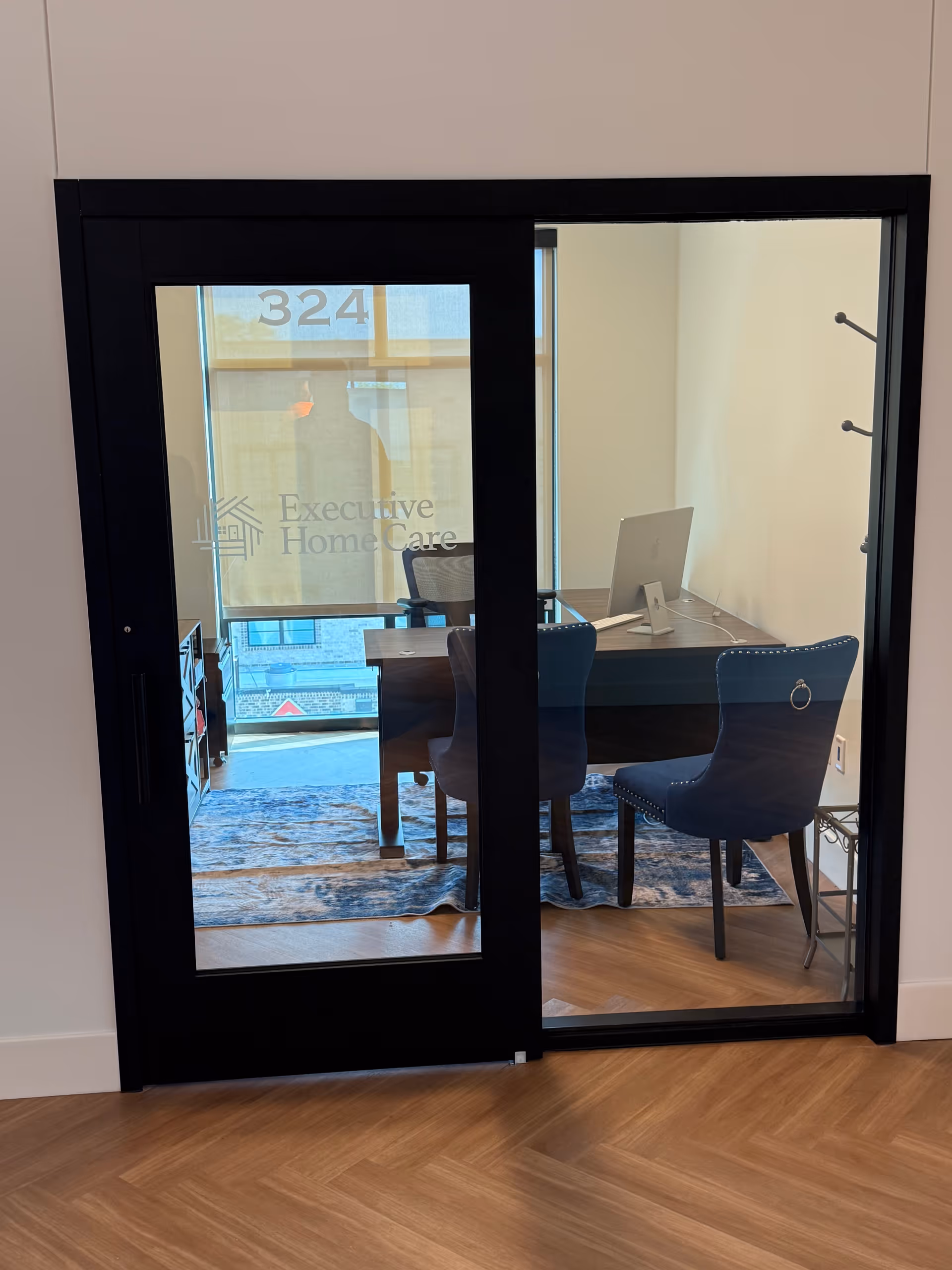 Office behind glass doors with desk, computer, chairs, and Executive Home Care logo.