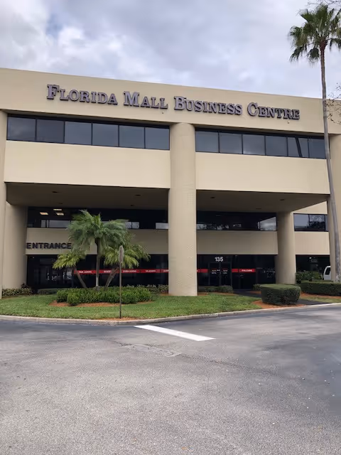Front view of a beige two-story building labeled Florida Mall Business Centre with palm trees