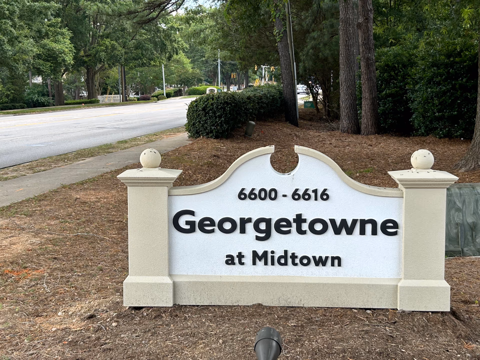 Outdoor sign reading Georgetowne at Midtown along a tree-lined street.