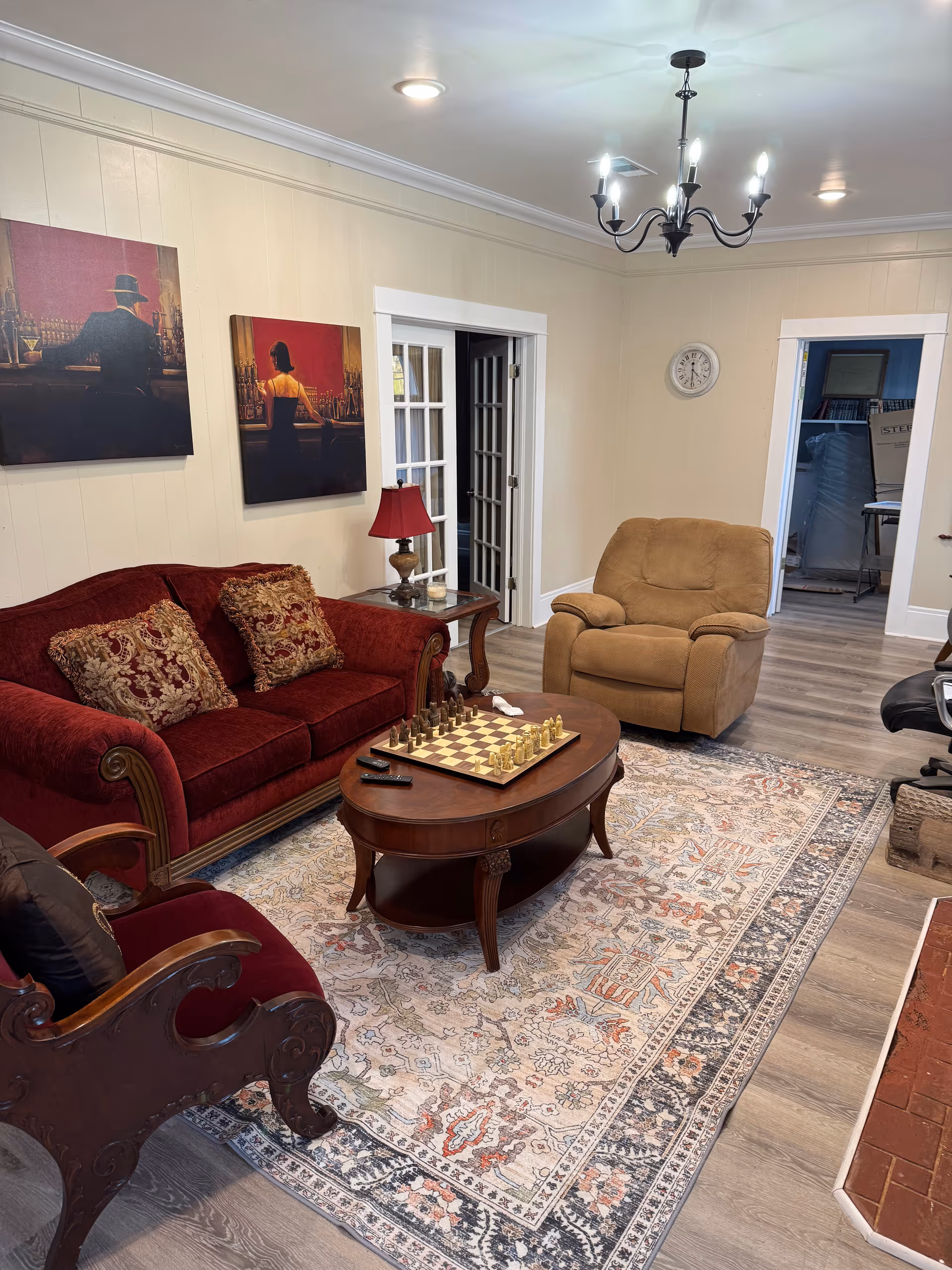 Cozy living room with red sofa, beige armchair, and chessboard on a coffee table.