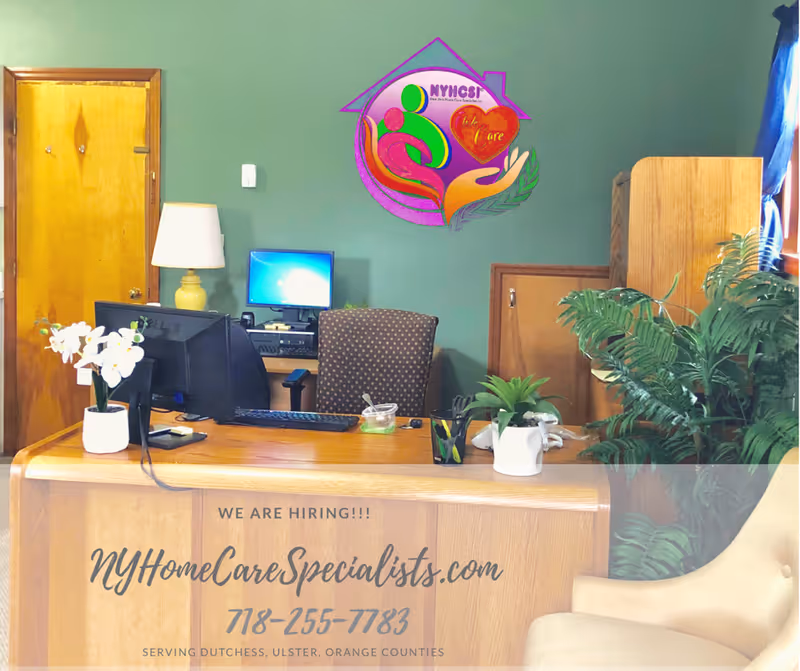 Reception desk with computer, plants, and a colorful logo on teal walls.
