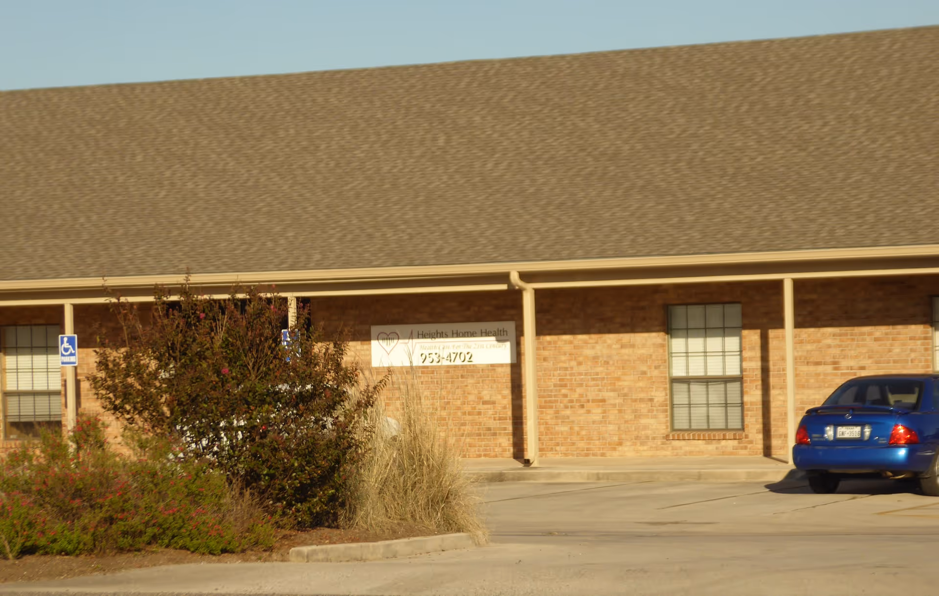 Brick, single-story facility exterior with Heights Home Health sign and a blue car.