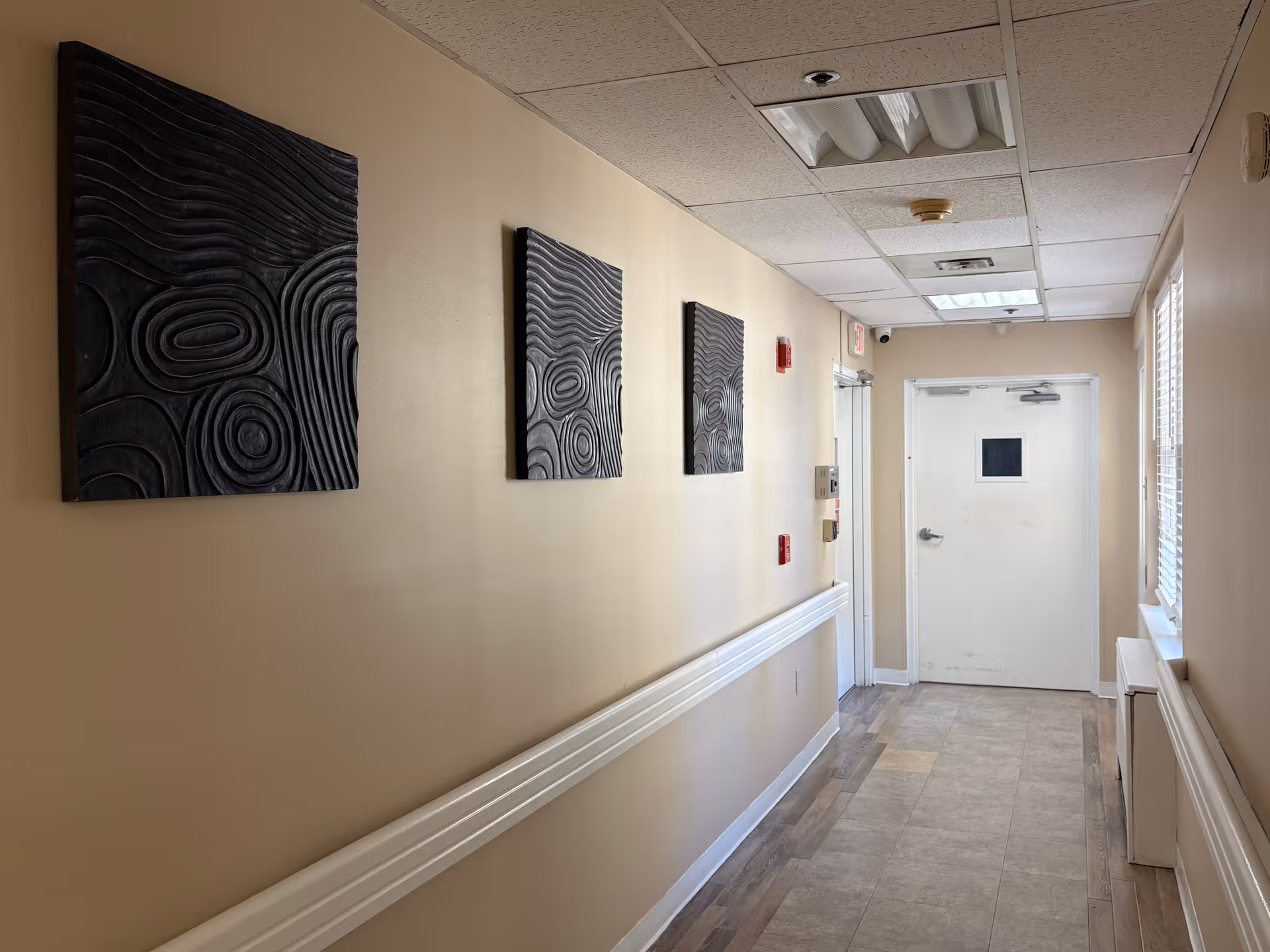 A beige hallway with abstract wall art and a white door at the end.