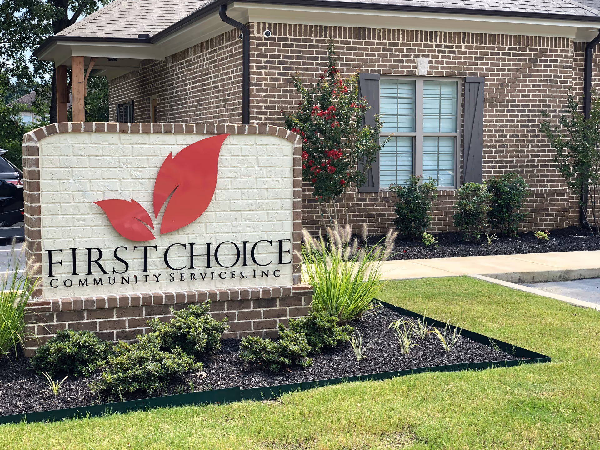 Brick building front with a large First Choice Community Services sign and landscaping.