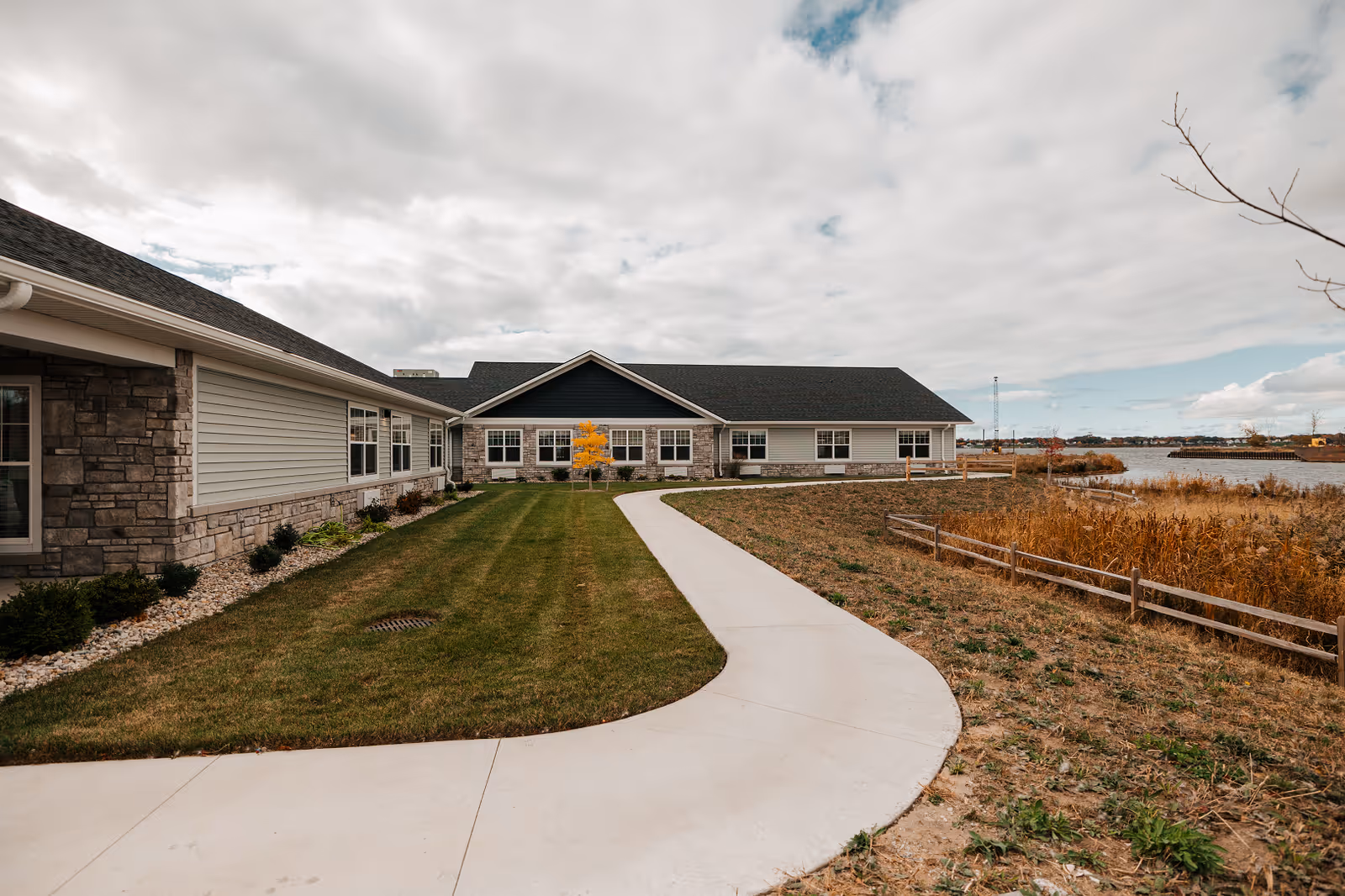 Exterior of Harbor Terrace Senior Living, a single-story building with curved walkway and lakeside view.