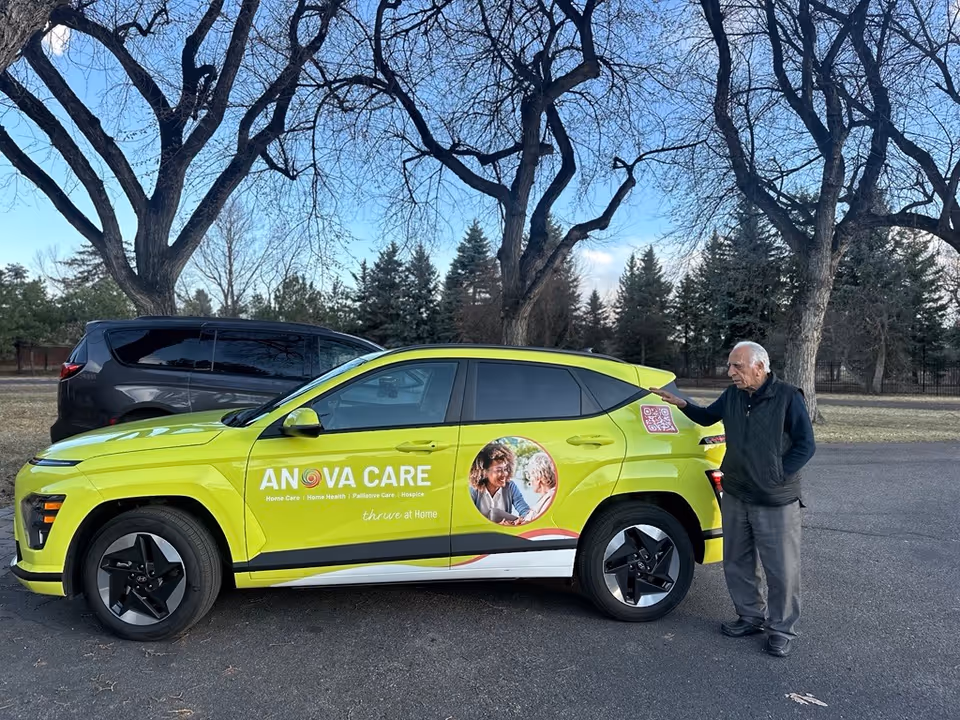 A lime-green Anova Care vehicle parked outdoors with an elderly man beside it.