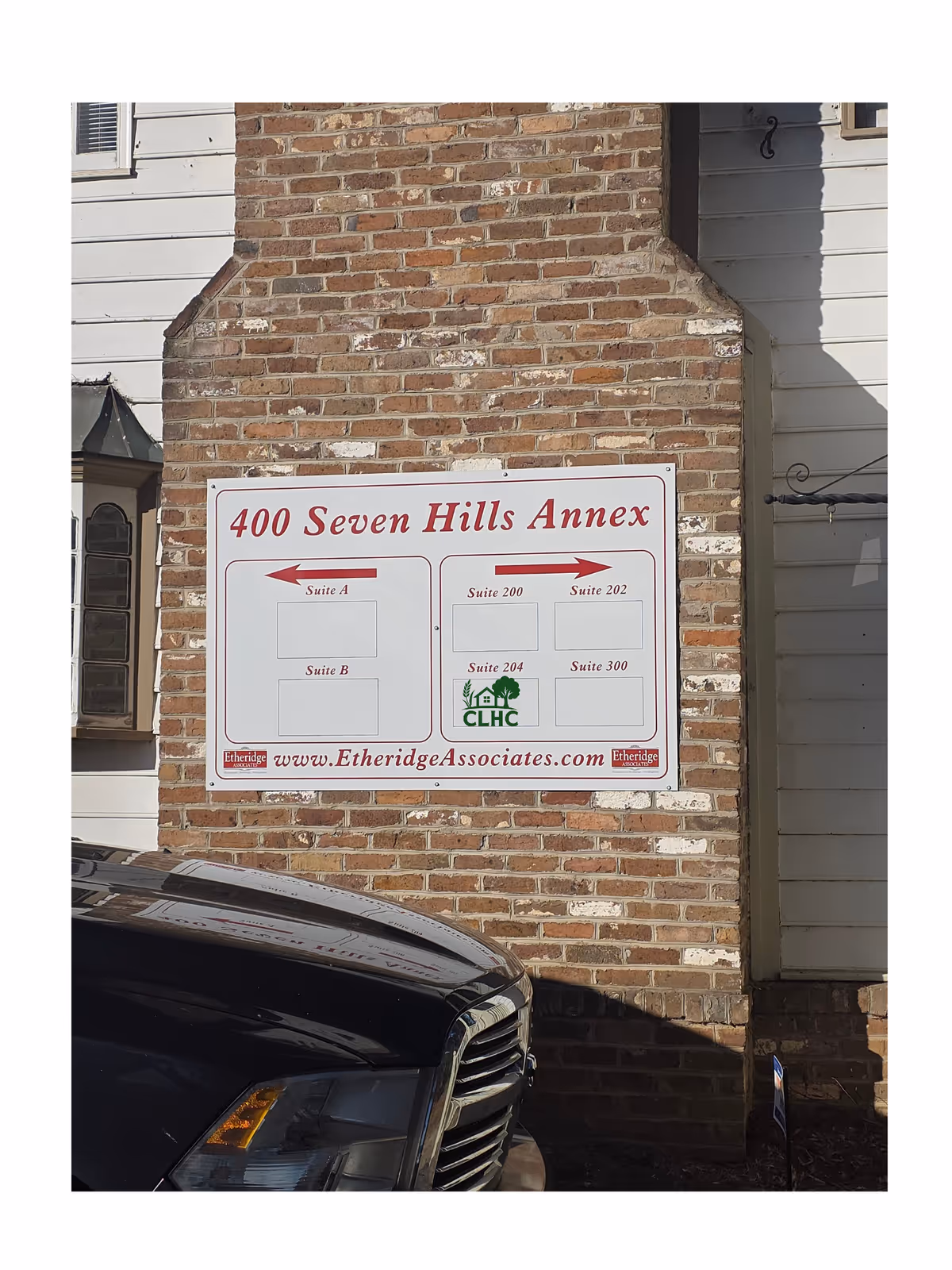 Brick exterior wall with a large sign reading 400 Seven Hills Annex and suite directions.