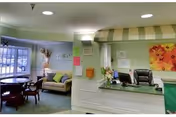 Reception desk with striped awning, pastel walls, and lounge seating in a nursing facility lobby.