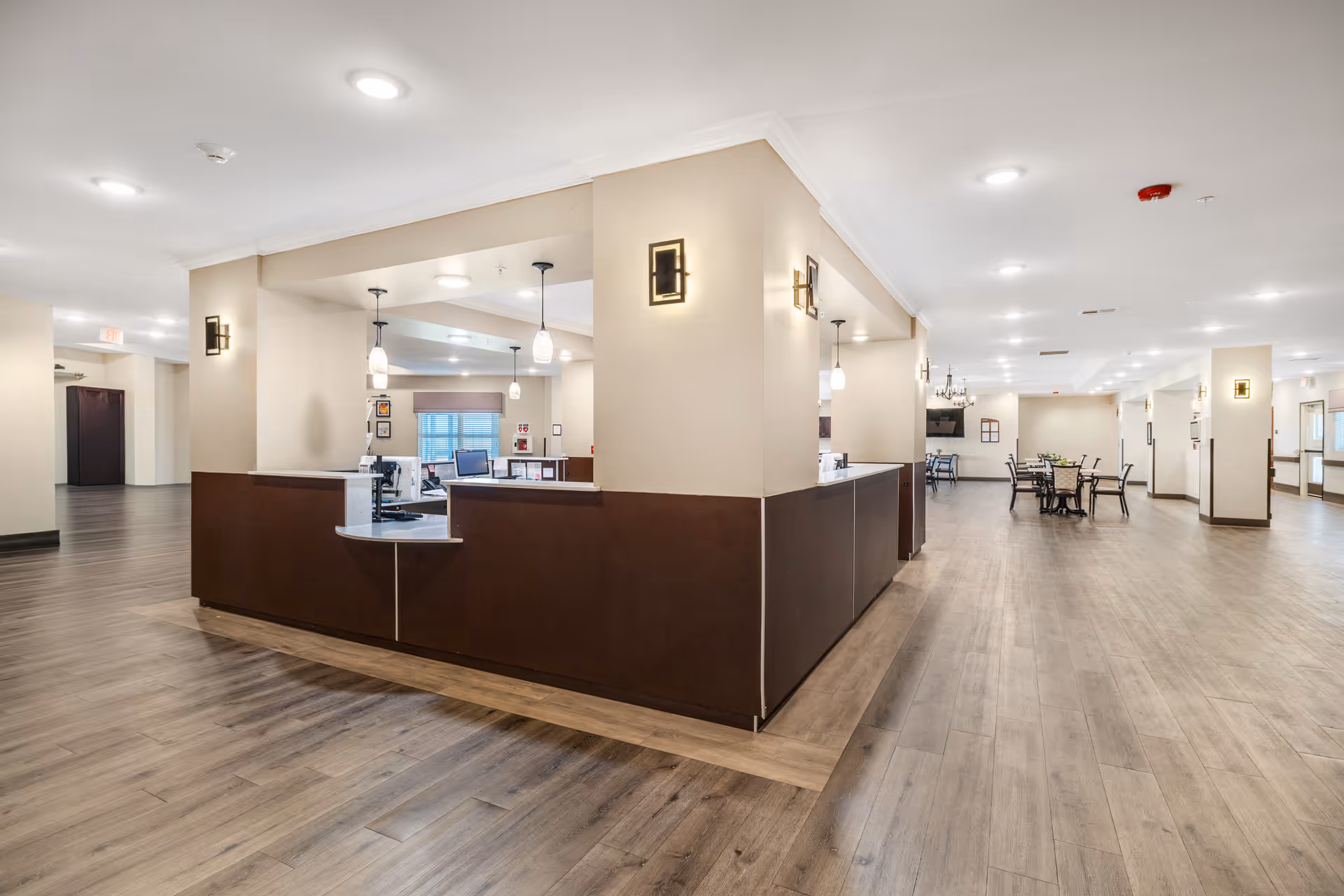 Bright lobby with a central reception desk and seating area in a senior living facility.
