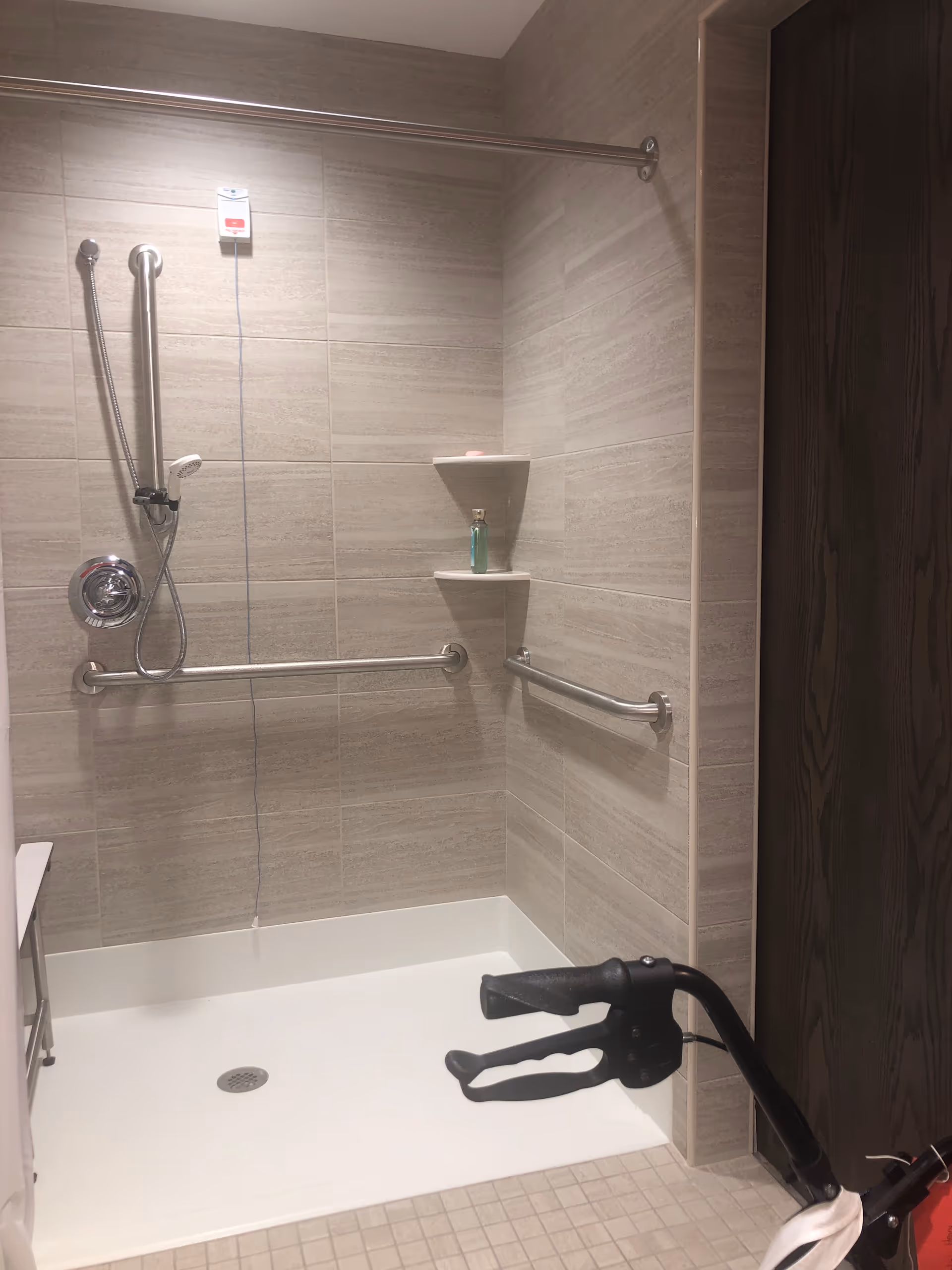 Accessible shower area with grab bars and a humanoid figure lying on the floor.