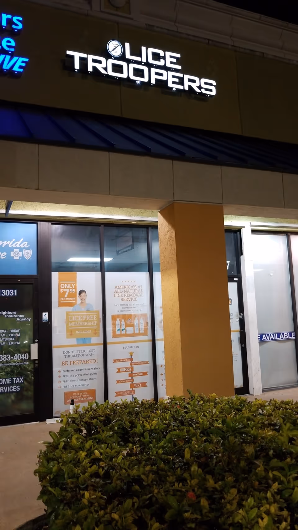Night exterior of a storefront with Lice Troopers sign and promotional posters.